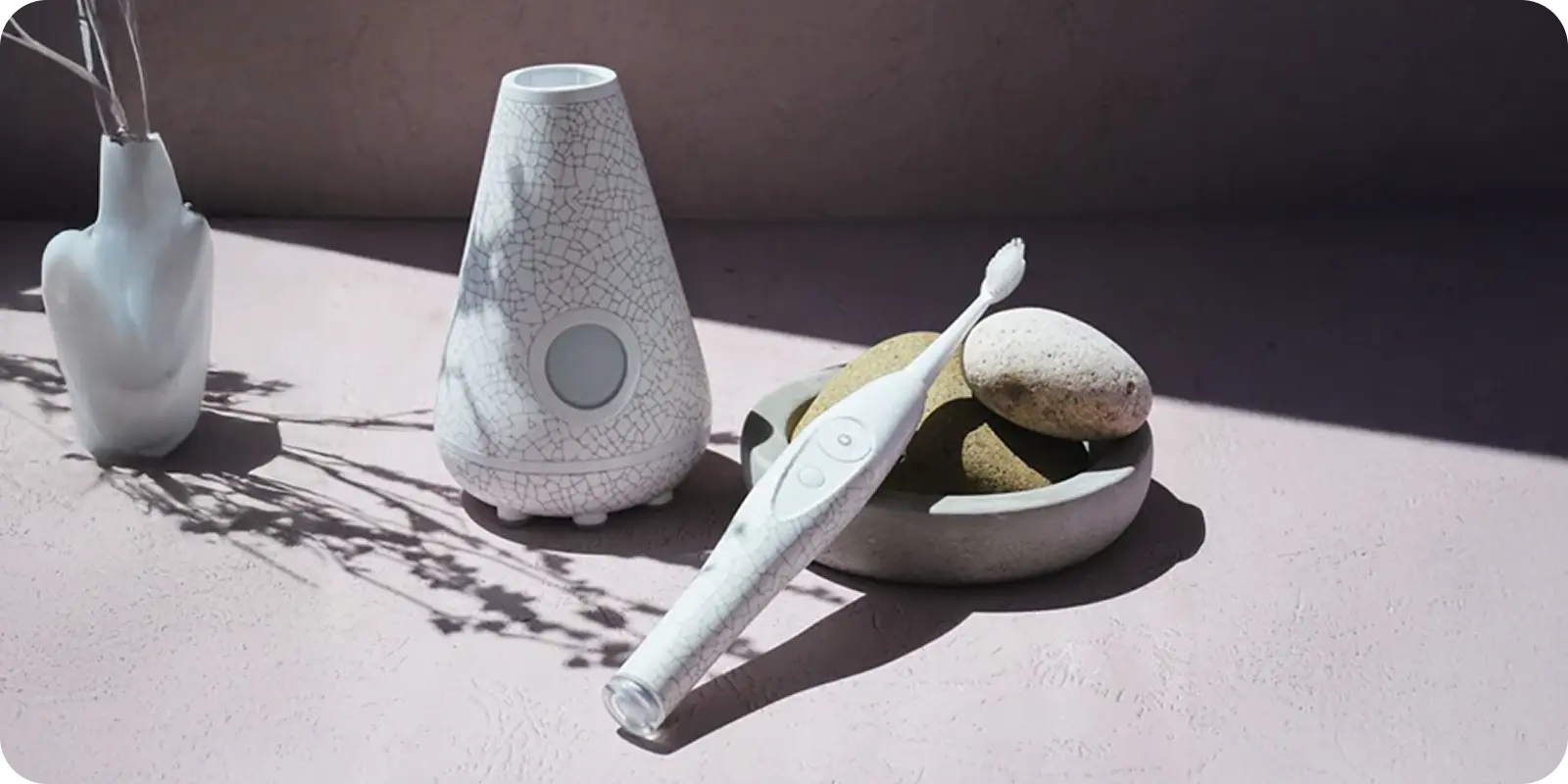 A white patterned toothbrush, charger, and pretty vase rest in sun on a pink surface—organized with ShipMonk.com’s easy touch. via ShipMonk.com