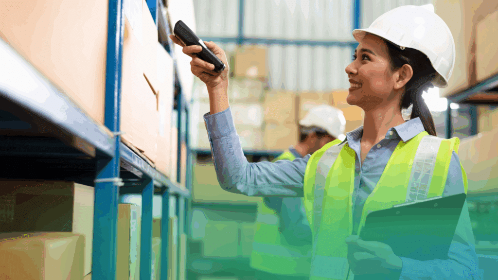 A cheerful woman in safety gear scans boxes on neat shelves, clipboard in hand—just another organized day at ShipMonk.com. via ShipMonk.com