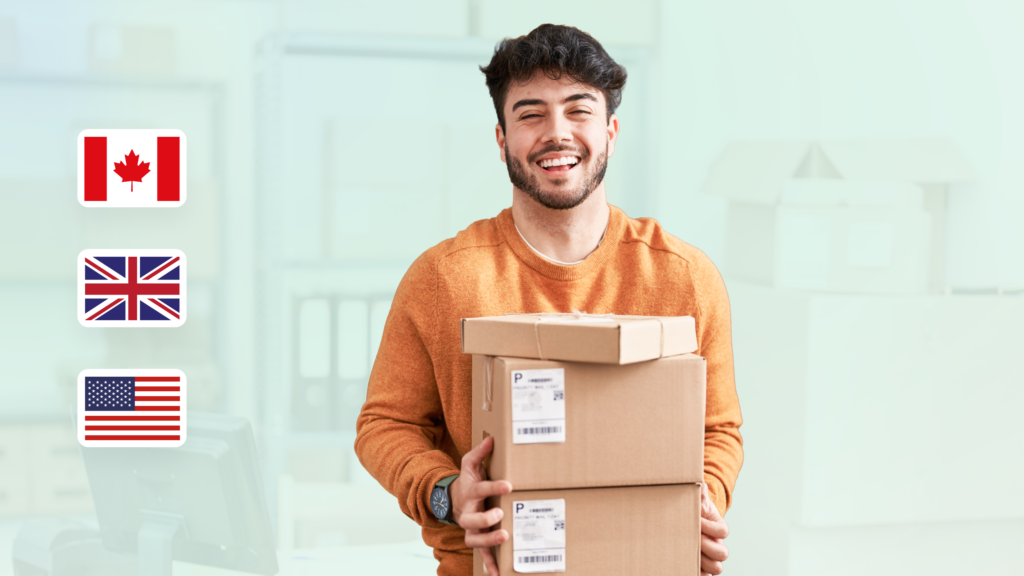 A cheerful man in a bright orange sweater lifts two boxes, ShipMonk.com-ready, with international flags and neat office shelves behind. via ShipMonk.com