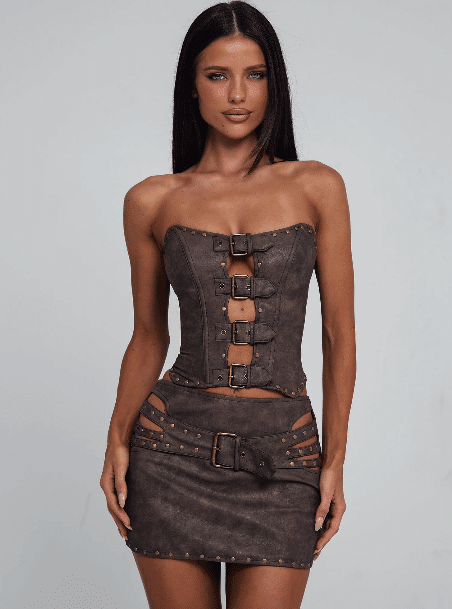 A woman in a chic brown corset and skirt, styled just right for ShipMonk.com’s Wellness Brand Fulfillment, shines on a gray backdrop. via ShipMonk.com